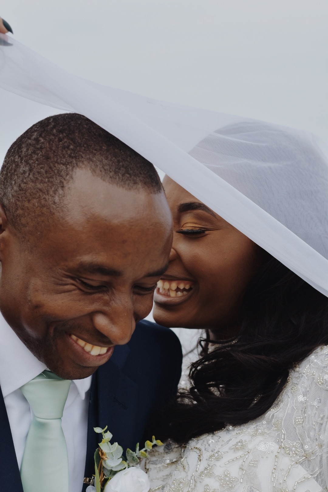 Bride and groom laughing beneath the veil